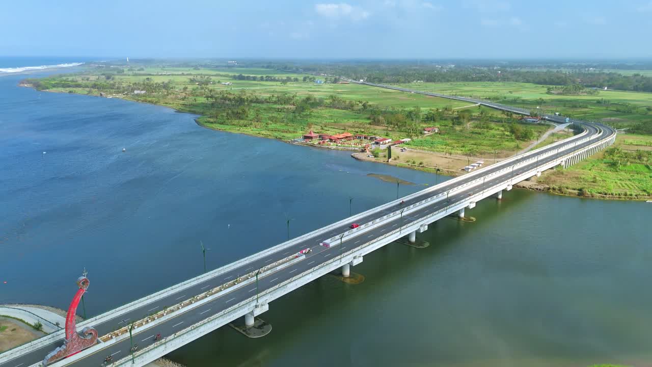 Aerial view of large bridge on the wide river and coastline on the background. Kretek II Bridge, Depok Beach, Yogyakarta, Indonesia. 4K drone footage.