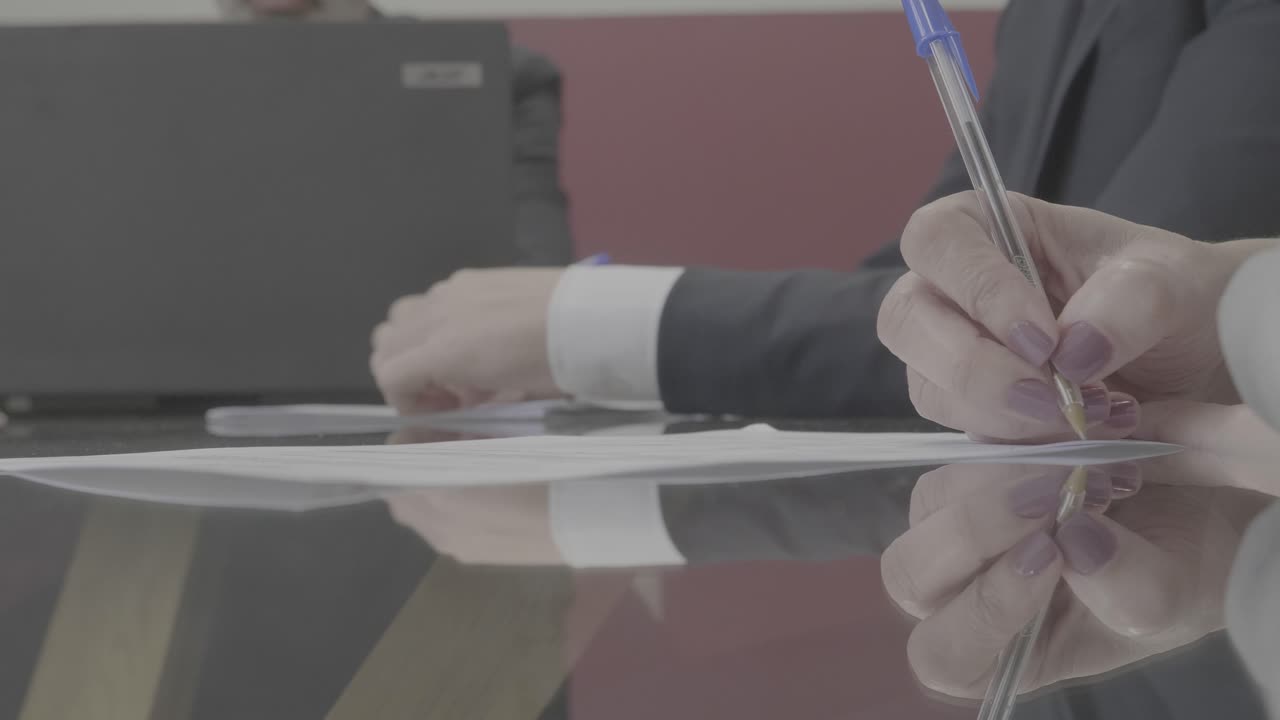 Pan of two people signing a contract