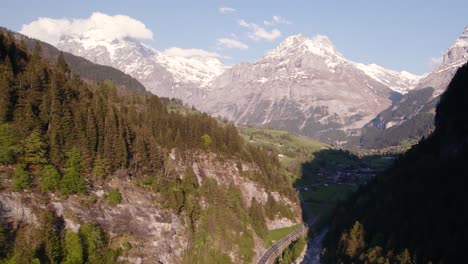 aerial drone footage pushing in at entrance of grindelwald village showing spectacular mountain views of swiss alps