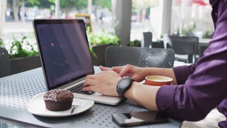 Asiatischer-Mann-Tippt-Auf-Einem-Laptop-Mit-Kopierplatz,-Während-Er-In-Einem-Café-Sitzt