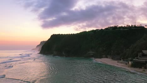 Costa-Aérea-De-La-Playa-De-Los-Acantilados-De-Uluwatu-Con-Puesta-De-Sol-Púrpura-Y-Rosa-En-Bali