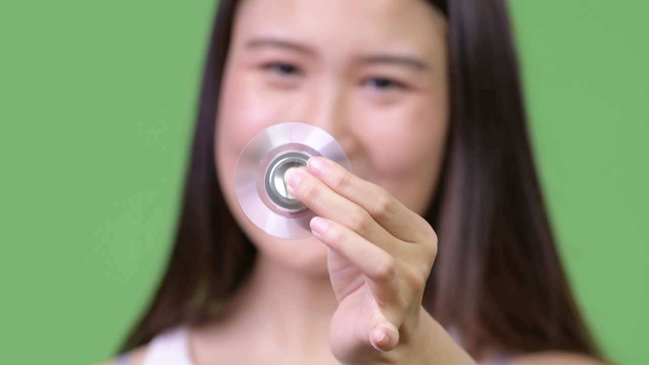Young beautiful Asian businesswoman playing with fidget spinner