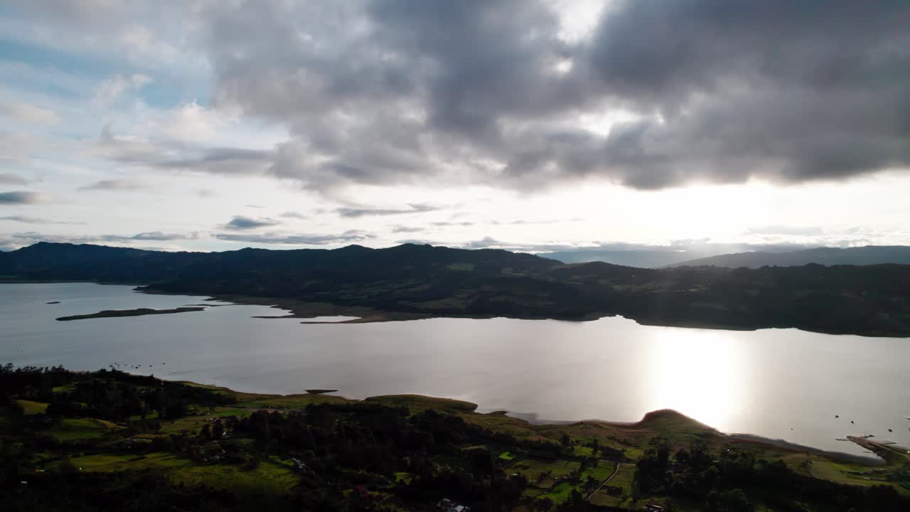 Drone pan right over the green hills and wide water expanse of Tominé Reservoir in Guatavita, Colombia
