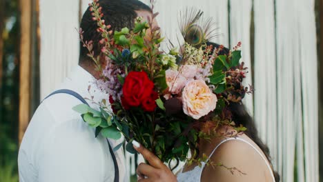 couple kissing with boho wedding bouquet