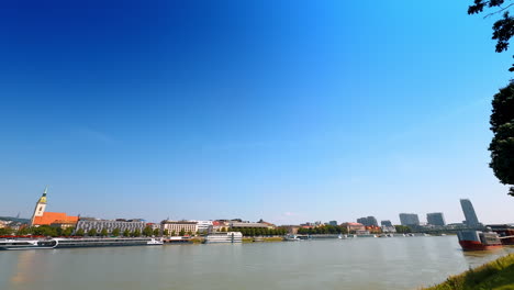 waterfront view under a clear blue sky. a vibrant riverside view showcases boats along the water with cities lining the banks under a bright blue sky
