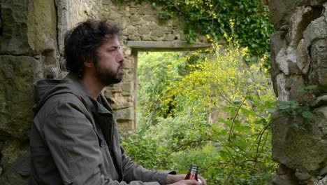 a hiker stops to drink coffee from his flask at old ruins along the trails of catalonia spain