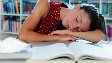 tired schoolgirl sleeping in library while doing homework