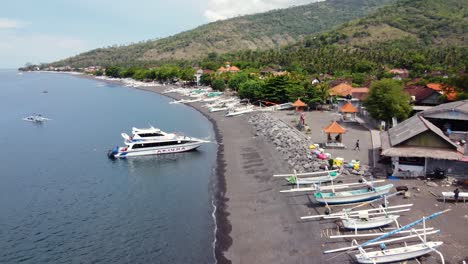 Barcos-De-Pesca-Jukung-Tirados-En-La-Playa-De-Arena-Negra-De-La-Aldea-De-Amed-En-Bali---Indonesia,-Antena