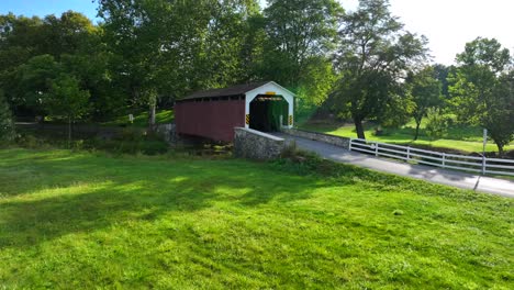 vehicle entering red covered bridge in rural usa