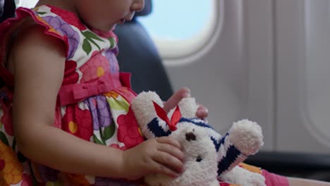 toddler in airplane playing with teddy bear