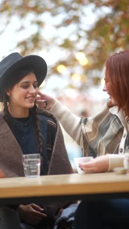 two women friends enjoying coffee outdoors in autumn