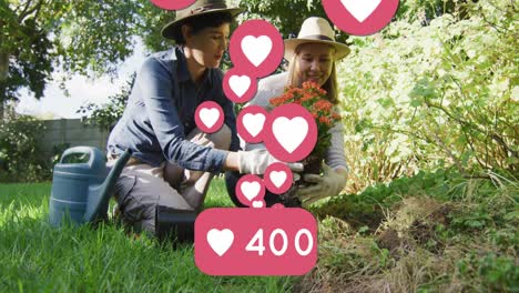 Animation-of-heart-emojis-and-numbers-over-happy-caucasian-female-couple-in-love-in-garden