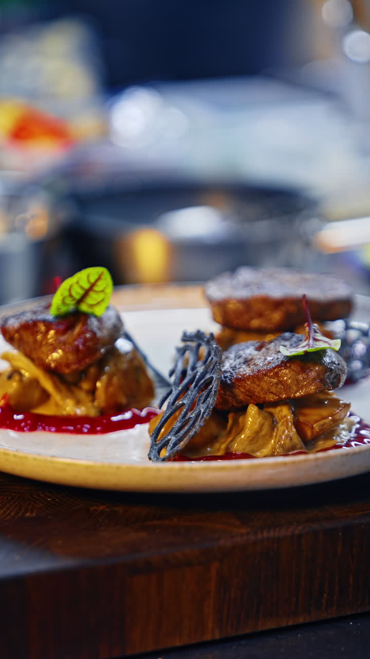 Chef's hands in black gloves put the leaves onto the dish. Serving the meat in the restaurant. Close up. Vertical video.