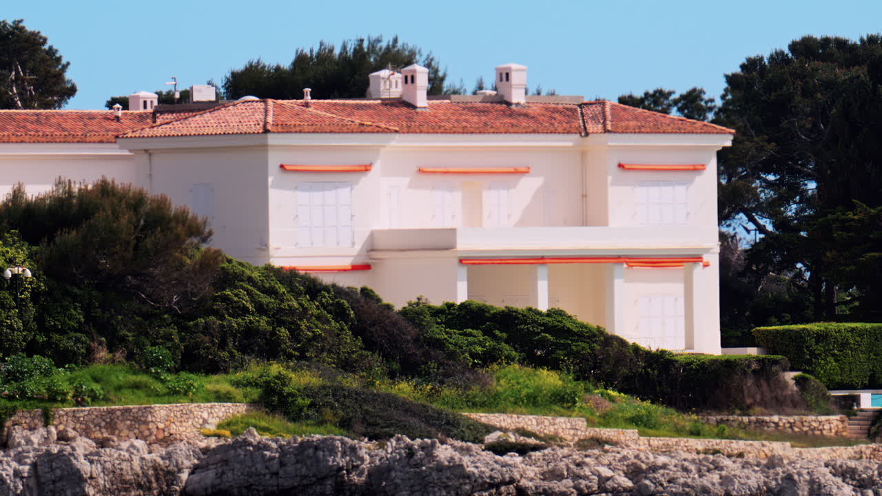 View of an orange villa surrounded by greenery on the shore, in the south of France