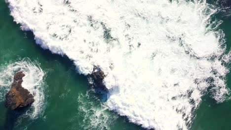 face down shot of waves violently crashing down on the rocks in the ocean on the english coastline in a small seaside town known as cornwall in the middle of the day