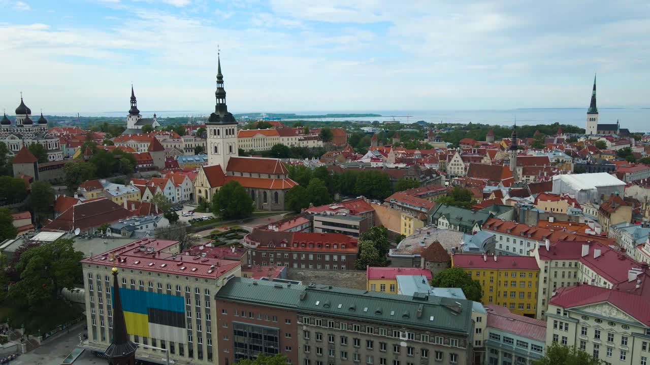 Gorgeous aerial drone footage of Tallinn medieval historic old town or central city world heritage location with red rooftops and church towers visible during a cloudy day in Estonia, monument visible