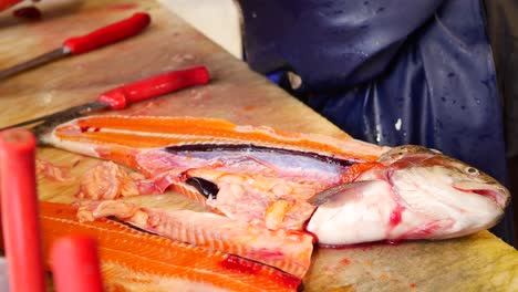 un pescador filetea un salmón fresco en un mercado de pescado