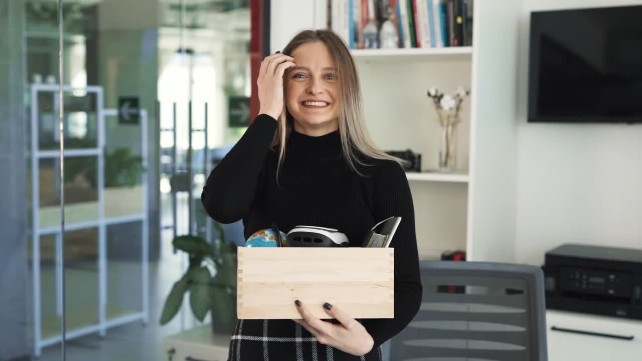 la joven acaba de llegar a su nuevo lugar de trabajo, con sus pertenencias en una caja, de pie en una oficina luminosa
