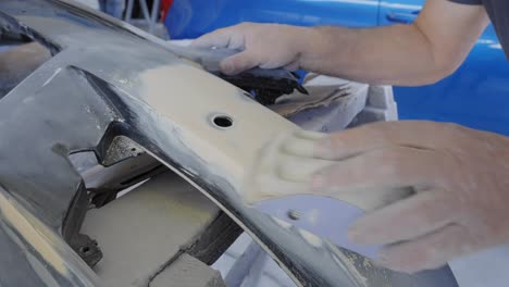 close-up of sanding a car bumper by hand to prepare for painting and restoration