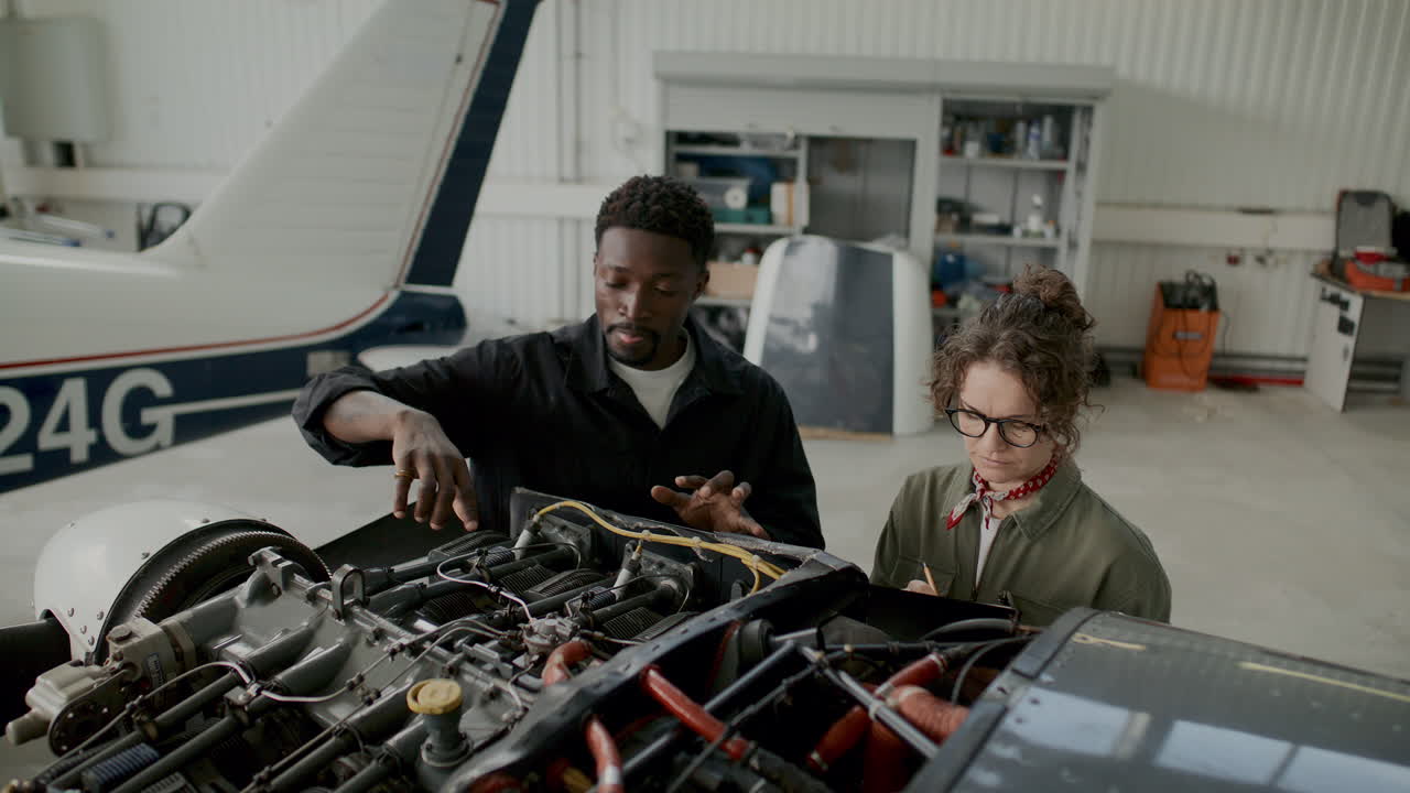 Diverse Mechanics Inspecting Aircraft Engine Components during Hangar Work