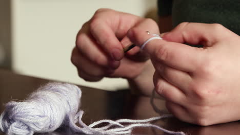 a close up shot of caucasian hands crocheting purple yarn