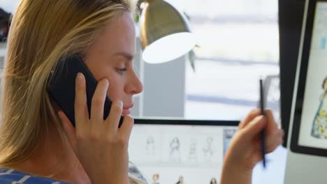 vista lateral de una diseñadora de moda caucásica hablando por teléfono móvil en la oficina 4k