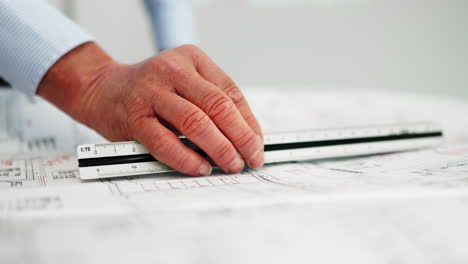 hombre anciano experimentado colocando una regla en el plan arquitectónico - mano de primer plano