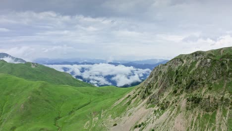 Aerial-View-Of-Foggy-Valley-Expanse-Behind-Sloping-Mountain-Pass-In-Summer