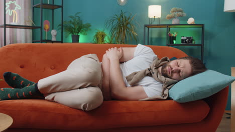 young man lying on sofa feeling sudden strong abdominal stomach ache gastritis problem diarrhea