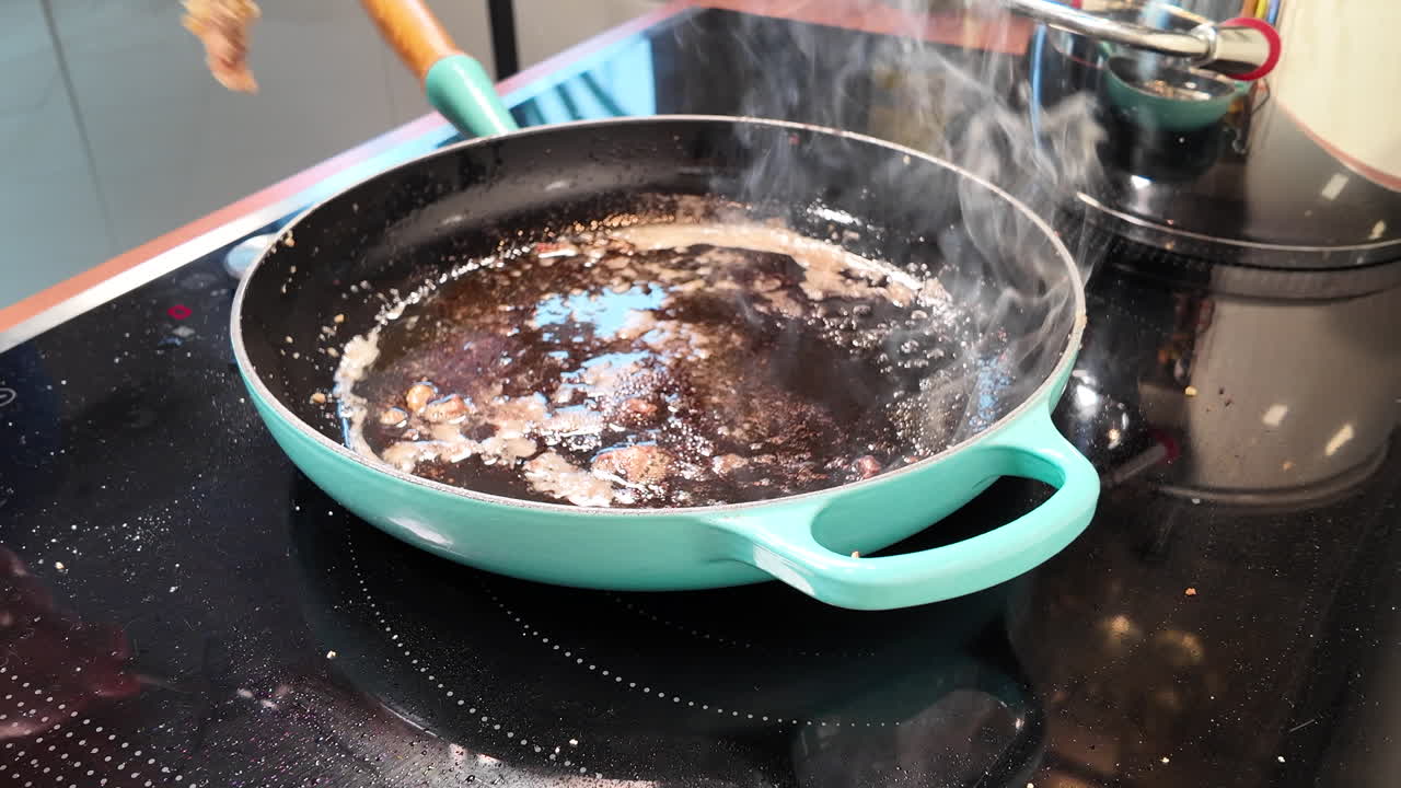 Primo piano di una cotoletta di maiale impanata girata in una padella con una forchetta mentre sfrigola nell'olio caldo
