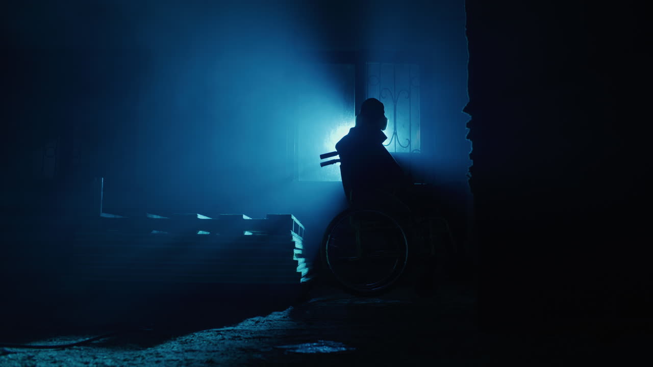 Silhouette di persona in sedia a rotelle in una stanza buia e nebbiosa