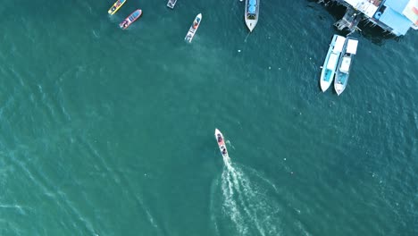 Pequeño-Barco-Navegando-Desde-El-Mar-Hasta-Los-Muelles-Del-Puerto-De-Sempora-Bajau-Laut,-Drone-Con-Vista-Superior-Disparado-Desde-Arriba