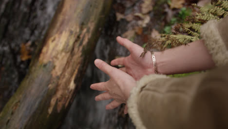 hands touching water in running stream