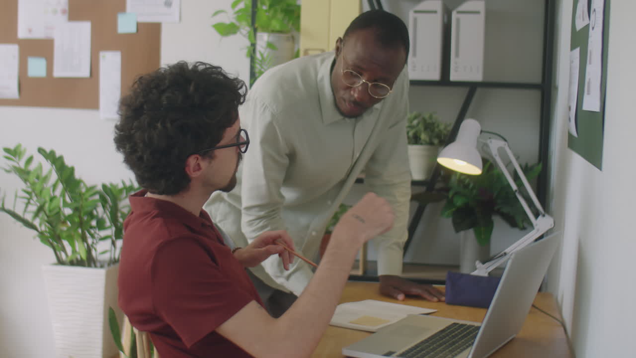Diverse Coworkers Discussing Project on Laptop in Office