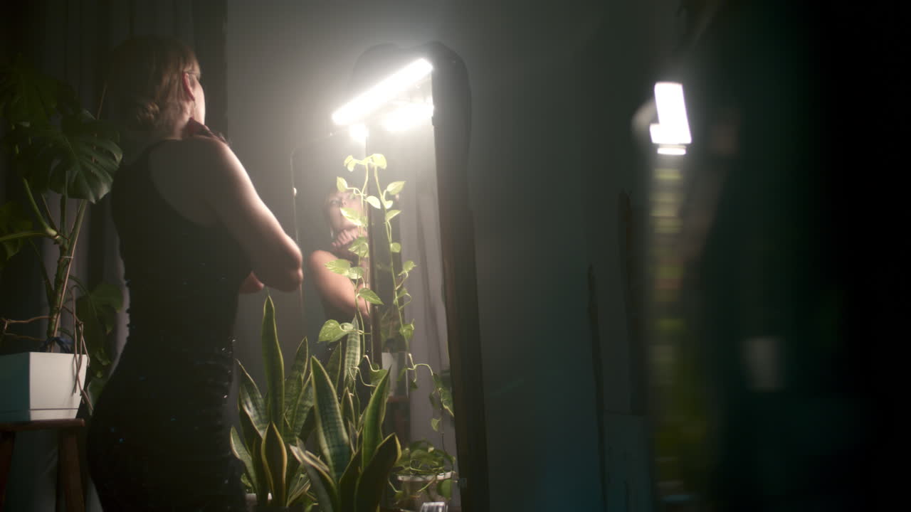 Woman in a black dress posing in front of a mirror at night