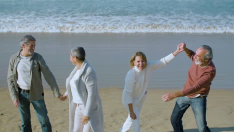 happy senior couple jumping on sea shore and hugging