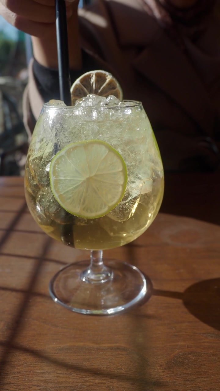 Persona che mescola un rinfrescante cocktail al lime in un caffè soleggiato