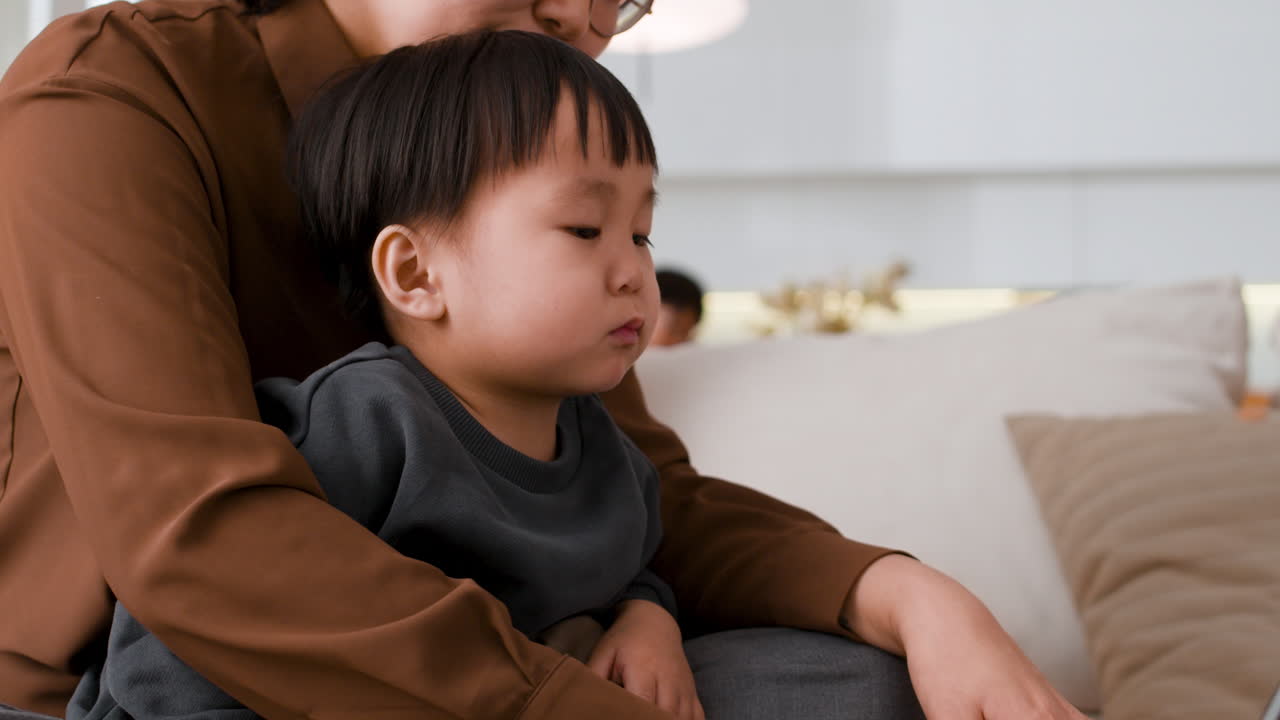 Mother teaching her toddler on a laptop