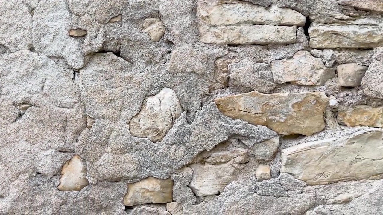Lenta panoramica della telecamera su un'antica parete in pietra calcarea con texture e muratura rustica in Provenza.