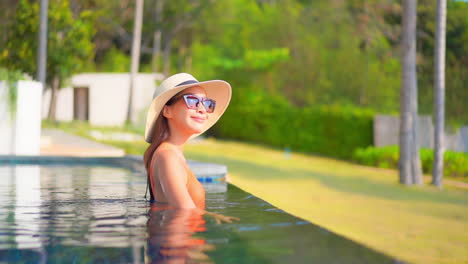 wealthy asian woman in swimming pool on tropical vacation enjoying on sunny day
