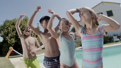 children dancing at poolside raising hands, having fun together.