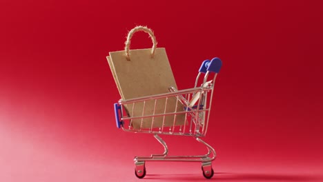 bolsa de regalo marrón en el carrito de compras sobre fondo rojo
