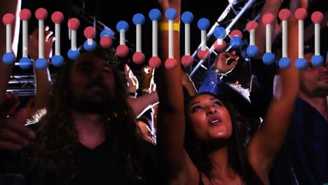 Animation-of-rotating-3d-dna-strand,-over-happy-diverse-crowd-dancing-at-music-festival