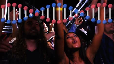 animation of rotating 3d dna strand, over happy diverse crowd dancing at music festival