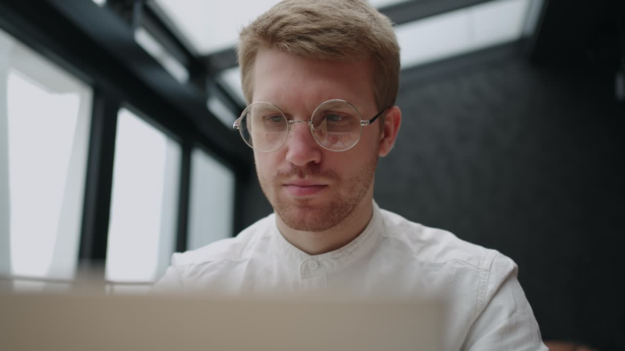hombre elegante con gafas para la visión está trabajando con la computadora portátil, concentrado y cara seria