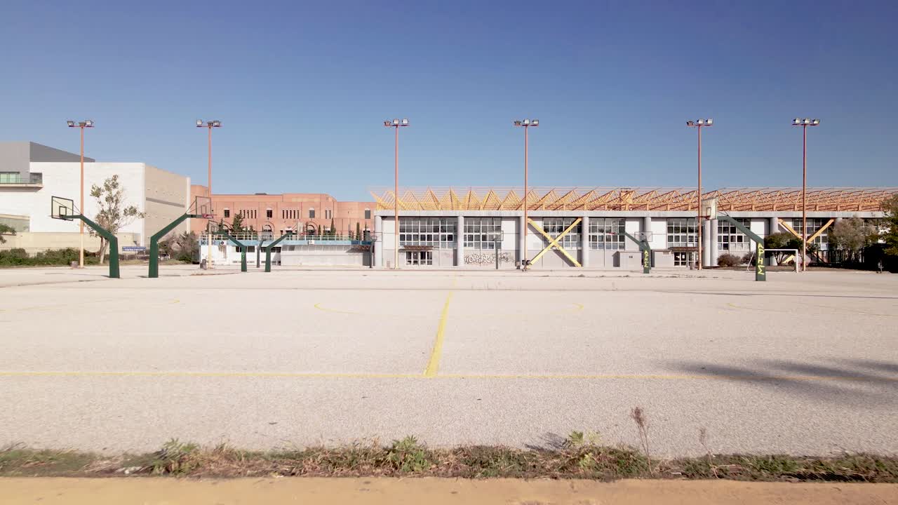 4k lowangle flying forwards drone clip over a basketball court in a sports complex in Thessaloniki, Greece