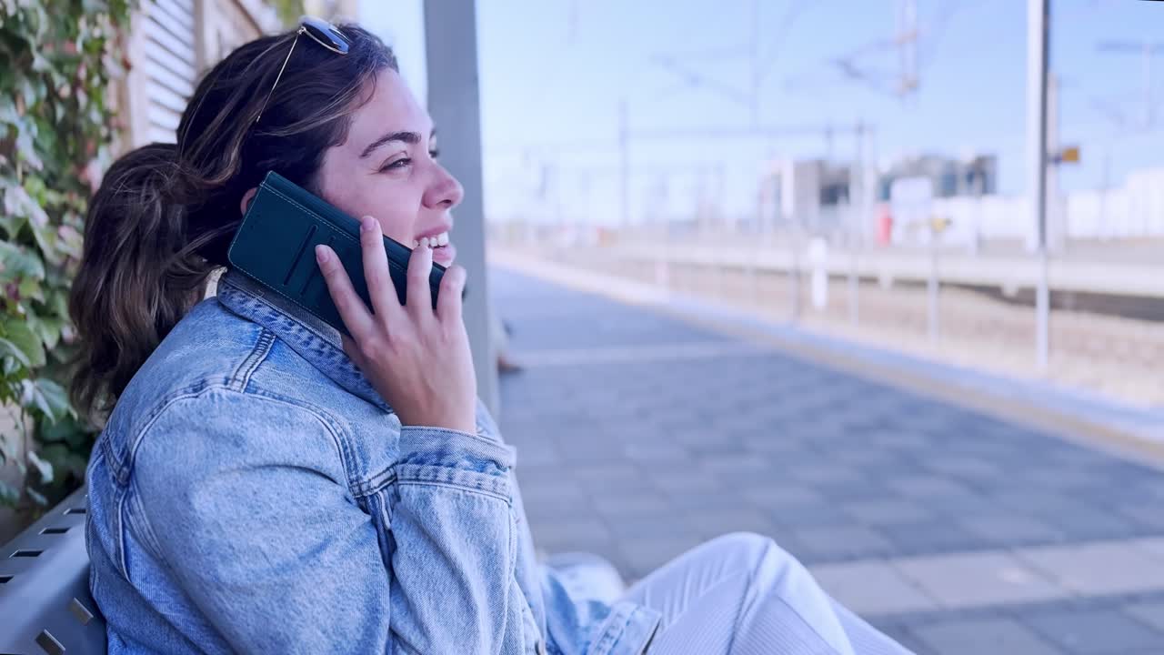 Donna felice che parla al telefono in una stazione ferroviaria