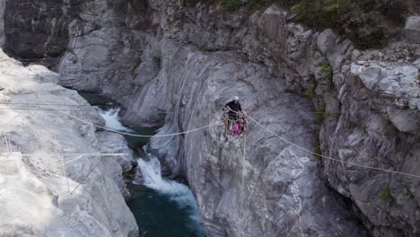 aerial shot of man crossing a gorge on a fixed cable and platform apparatus in nepal