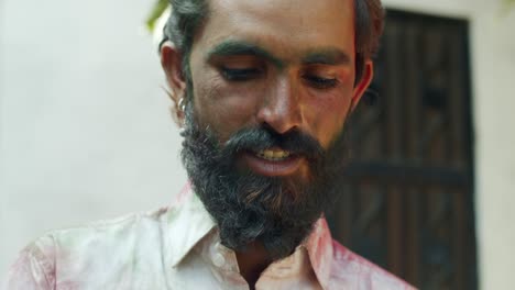 indian man close-up of face smeared with bright holi colors