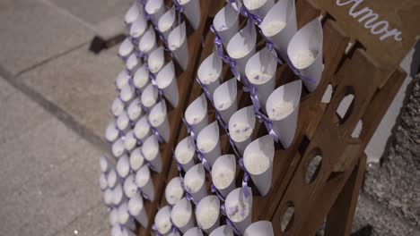 rows of white cones filled with rice, tied with purple ribbons, arranged on a wooden stand labeled amor